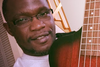 Close portrait of Patrick Mose holding an acoustic guitar