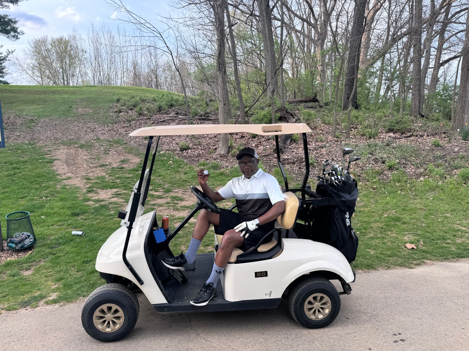 Patrick Mose in a golf cart on the course, holding a golf ball