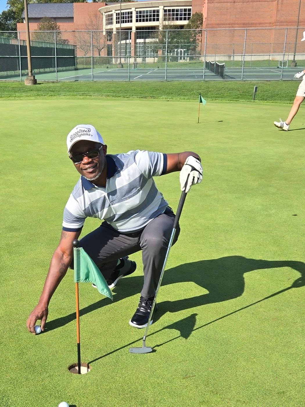 Patrick Mose retrieving a ball from the hole on a sunny green